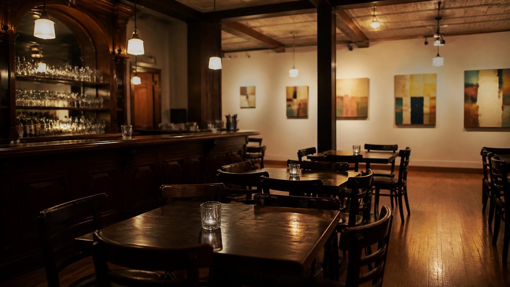 Empty warm pub tables beside a white gallery wall in a historic interior