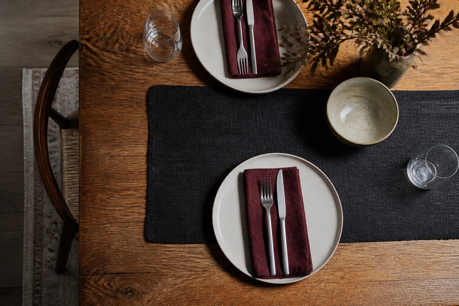 Cream tableware, simple flatware, clear glassware, and textured linens on warm wood